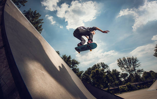 faible angle de vue d'un jeune homme skateboarding en plein air. - ollie photos et images de collection