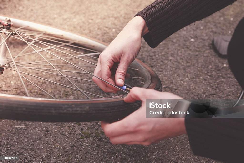 Woman fixing her bike Young woman is fixing her bike and pumping her tires Activity Stock Photo