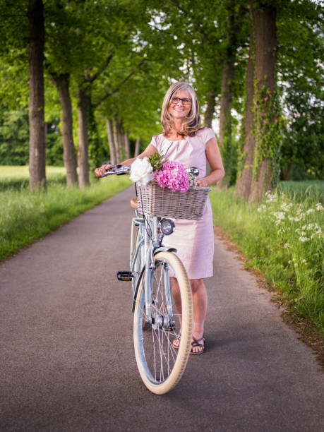 istock Woman standing with her bicycle in a summer park 480198312