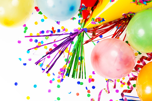 Party, birthday or carnival backgrounds. Overhead view of pink colored accessories like balloons, confetti, candies, drinking straws and streamers shot on blue background. High resolution 42Mp studio digital capture taken with SONY A7rII and Zeiss Batis 40mm F2.0 CF lens