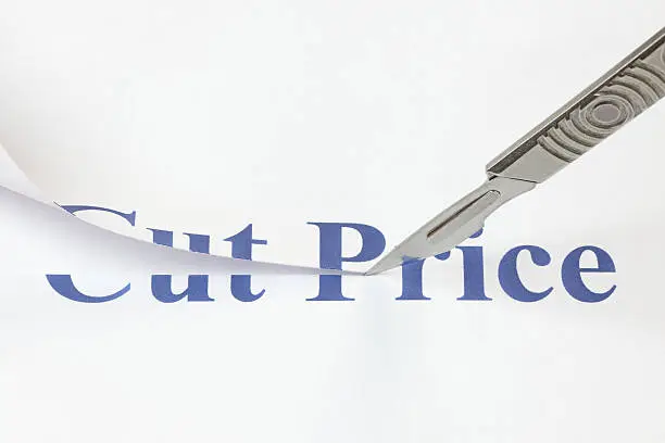 A scalpel cutting through the words Cut Price. Concept denoting a cut in price to encourage more spending or due to a poor economic performance.