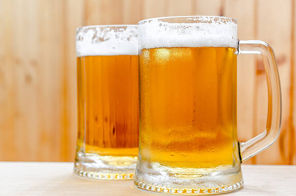 Two beer mugs on the wooden background stock photo