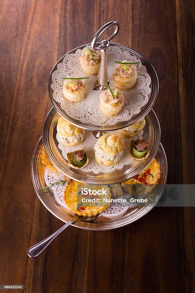Savory pastry selection A variety of delicious savory pastries and bites served on a silver cake stand. The selection includes quiches, spring rolls, scones with chicken and seafood. 2015 Stock Photo