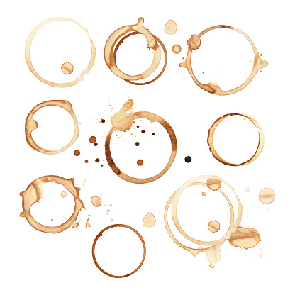 Different sized and shaped black coffee rings are isolated on a white background with a clipping path. There are splashes and drops of coffee stains around round rings where the cups sat on the paper. The stains have soaked and smeared in different shapes and sizes.