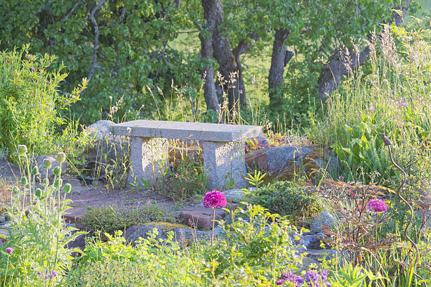 Peaceful feeling with a garden bench made of stone (granite) in the center of garden flowers in the morning light
