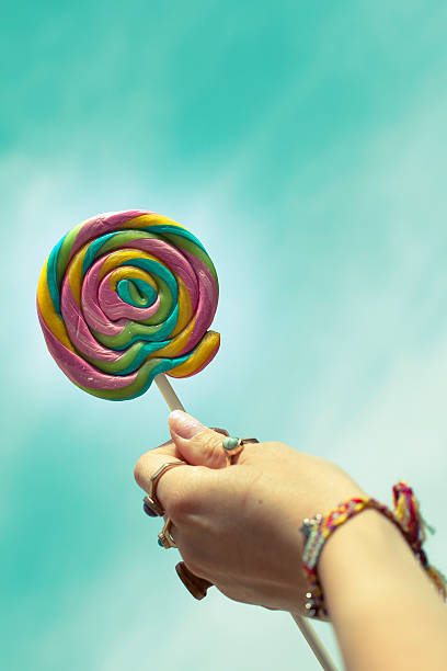 istock Hand holding colorful spiral lollipop over sky 480231458