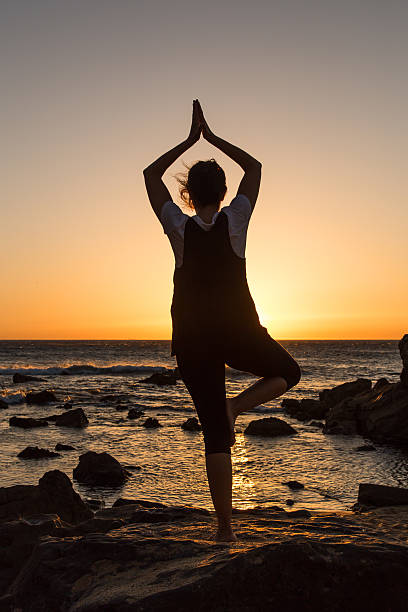 istock Silhouette young woman practicing yoga on the beach at sunset. 480234958