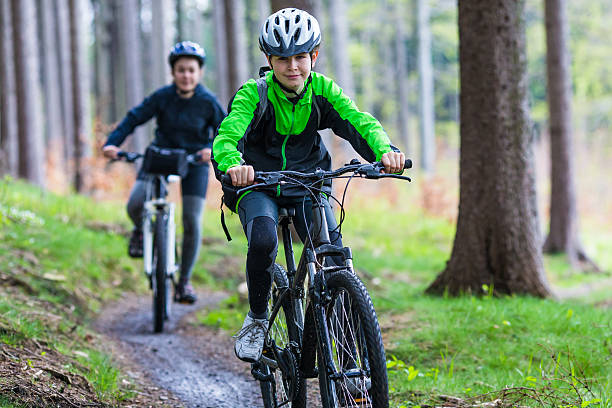 adolescente ragazza e ragazzo in bicicletta nella foresta di montagna - cycling teenager action sport foto e immagini stock