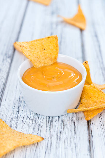 Nachos with Cheese Dip Nachos with Cheese Dip (close-up shot) on an wooden table cheese dip stock pictures, royalty-free photos & images