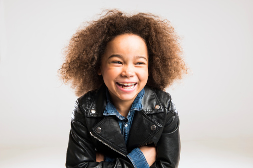 A happy little multi-racial girl with a beautiful face stands close to camera.