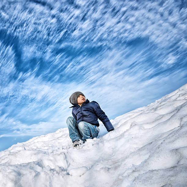 Young Asian boy wearing down jacket and winter hat in cold winter environment.