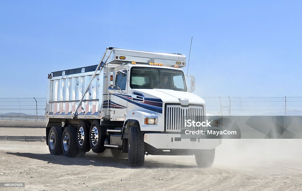 Dump truck at work Man driving a dump truck and picking up dust. Dump Truck Stock Photo