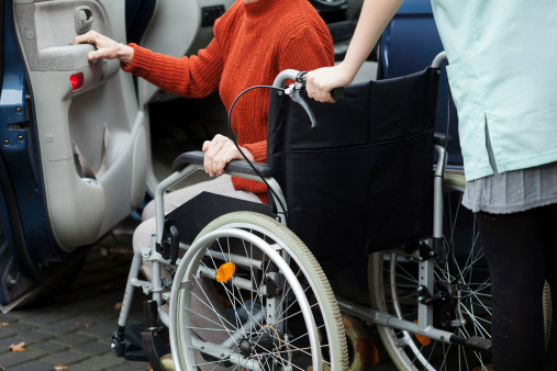Caregiver helping disabled lady get into the car