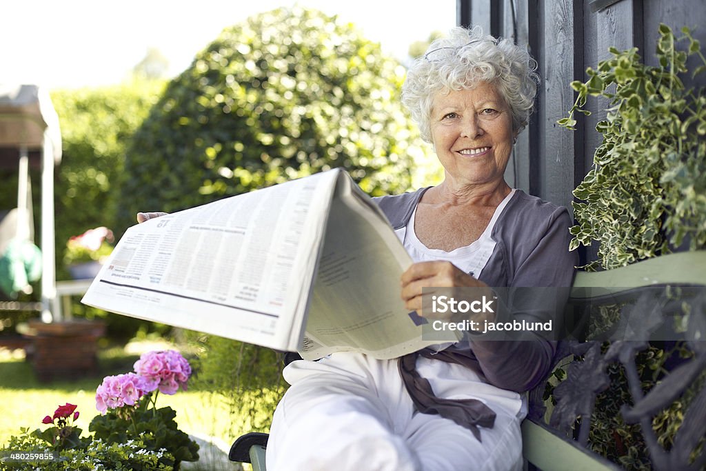 Senior woman reading eine Zeitung im Garten des Hotels - Lizenzfrei Gartenanlage Stock-Foto