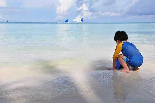 Child plays sand at white beach