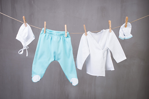 White baby goods hanging on the clothesline on grey background