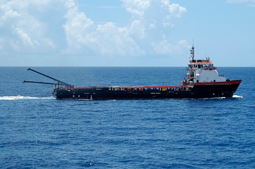 A supply vessel with two cranes deployed with seismic air gun arrays. A small seismic operation used for borehole testing.
