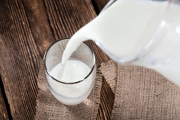 milk being poured into a glass, bright blue backgound