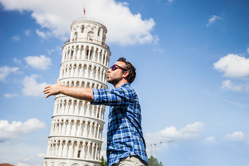 Young tourist having fun in Pisa close to the leaning tower.