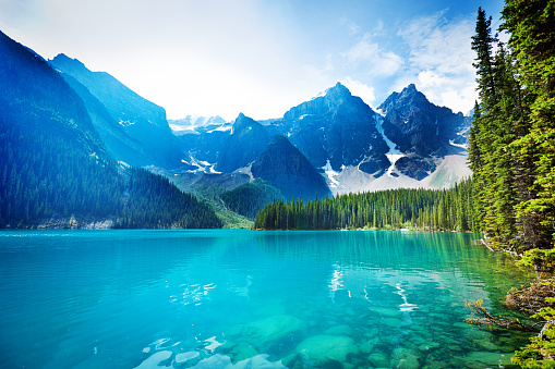 Lake Moraine in the Banff National Park, Alberta, Canada, features clear emerald water and snow-capped peaks of the Canadian Rockies mountain range. The scenic landscape is a famous place and a favorite tourist travel destination for North American great outdoors nature vacations. horizontal format with copy space and no people.