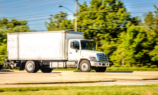 A large white cargo truck running swiftly through the highway.