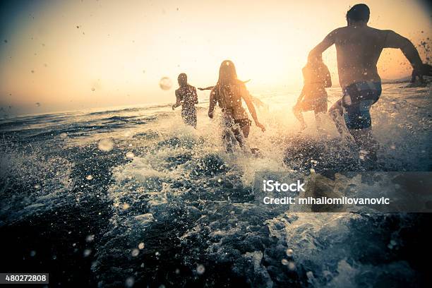 Group Of Friends Running Into The Water Stock Photo - Download Image Now - Beach, Community, Jumping