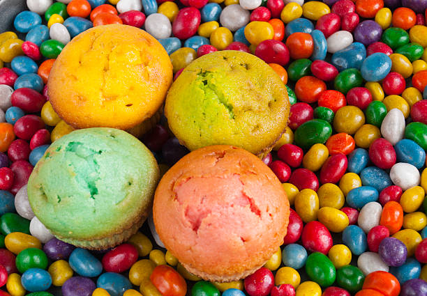 four tasty muffin lie on small colorful candy background