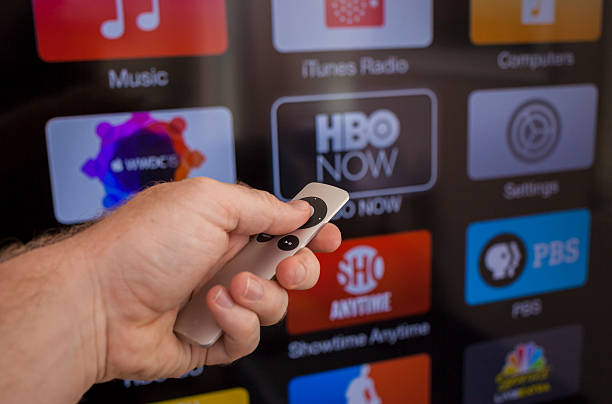 Apple TV Las Vegas, USA - July 8, 2015: Apple TV being used on a flatscreen TV. The young males hand can be seen holding the Apple TV remote browsing the channels that are available to stream TV content. showtime stock pictures, royalty-free photos & images