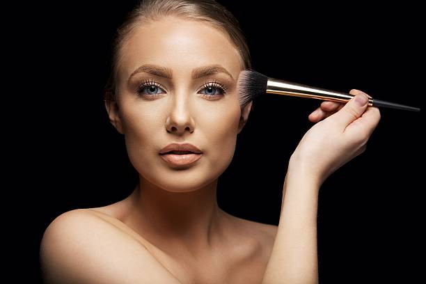 istock Pretty young woman applying make up with a brush 480288897