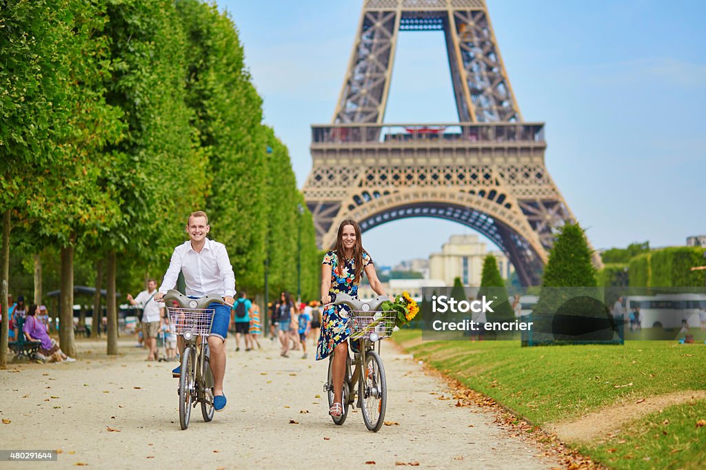 Romantic couple in Paris on a summer day Romantic couple riding bicycles near the Eiffel tower in Paris Paris - France Stock Photo