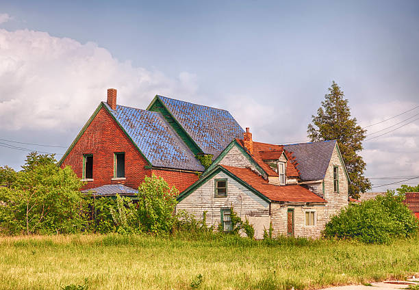 Abandoned House In Detroit Detroit, Michigan - June 9, 2015: An abandoned house with broken windows symbolizes urban decay in post-industrilal Detroit. The house is located in Highland Park next to an empty lot full of weeds   highland park michigan stock pictures, royalty-free photos & images