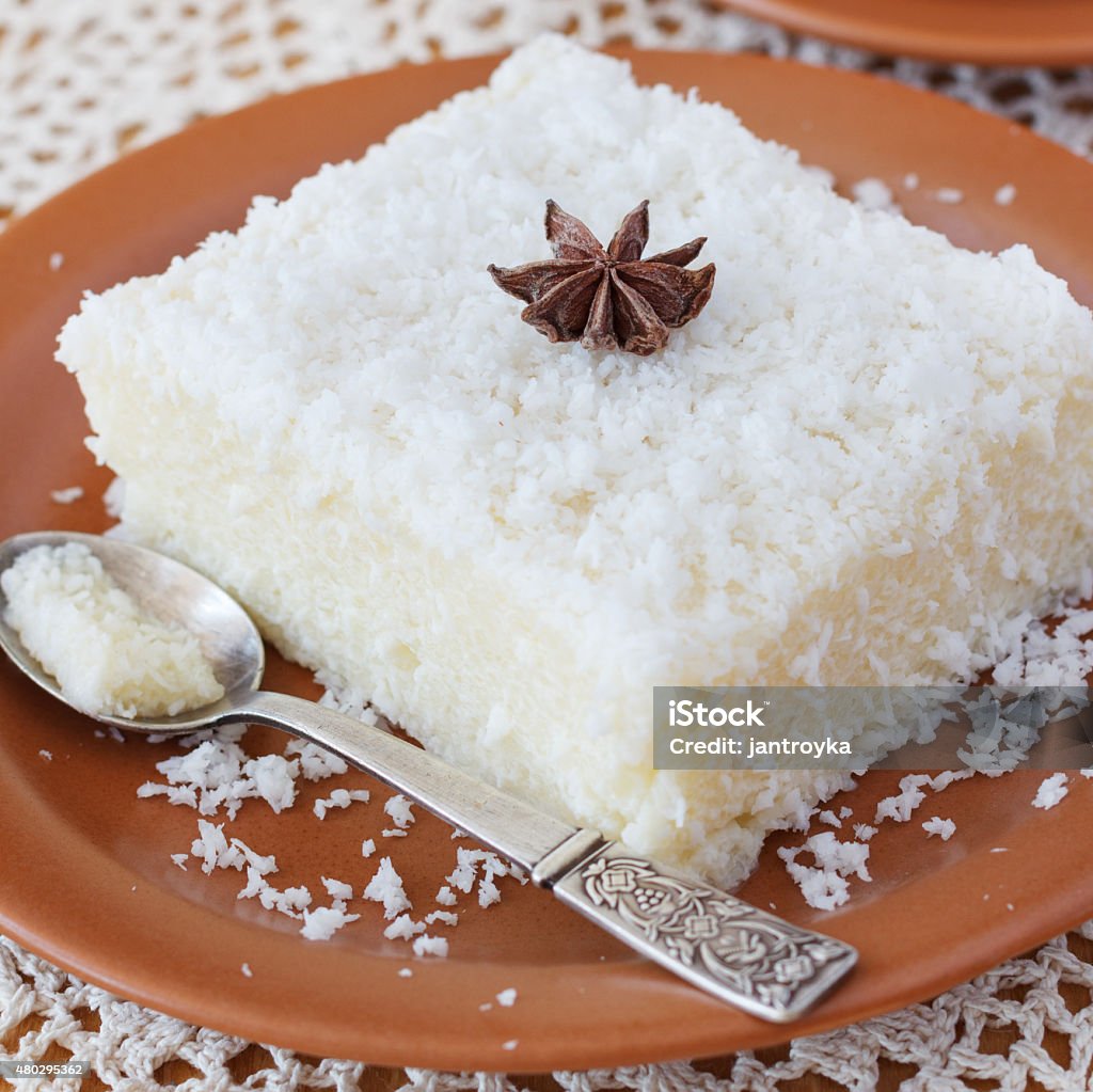 Sweet couscous (tapioca) pudding (cuscuz doce) with coconut Brazilian traditional dessert: sweet couscous (tapioca) pudding (cuscuz doce) with coconut on plate with spoon and cup of coffee on wooden table. Selective focus 2015 Stock Photo