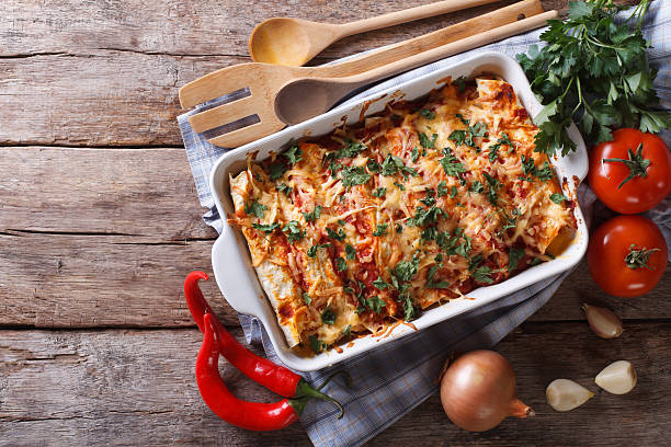 Mexican enchilada in a baking dish horizontal top view Mexican enchilada in a baking dish with the ingredients on the table. horizontal view from above omelet rustic food food and drink stock pictures, royalty-free photos & images