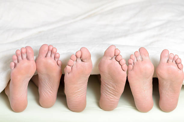 istock Three pairs of feet in bed 480297134