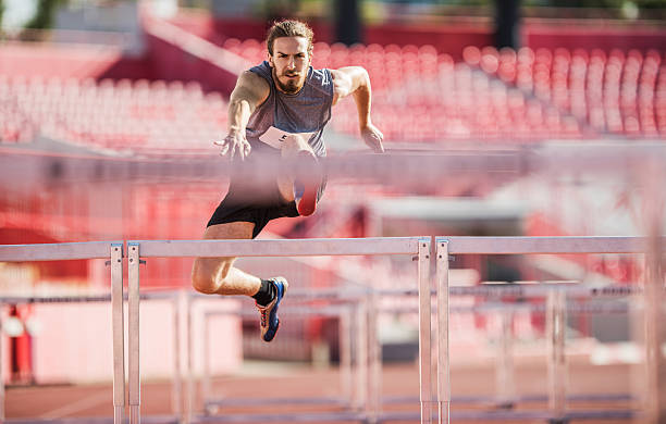 istock Young determined athlete jumping hurdles on a race. 480304230