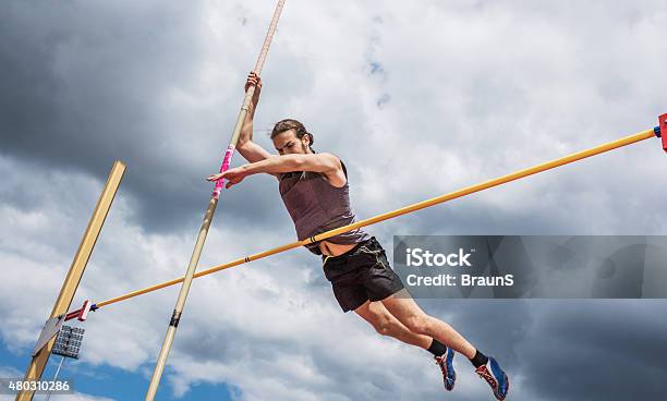 Male Athlete Performing High Jump Against The Sky Stock Photo - Download Image Now - Pole Vault, Pole, High Jump