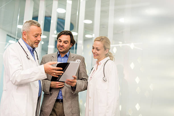 istock Mid adult businessman going through reports with two doctors. 480310970