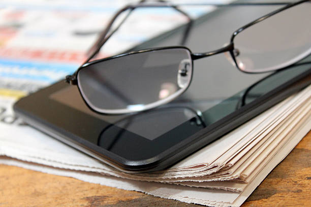 Newspaper, tablet, and glasses stock photo