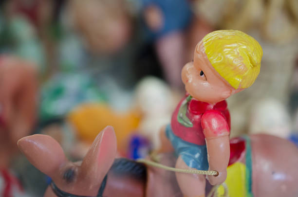 A vintage doll from 1950s sitting in front of a yellow toolbox.