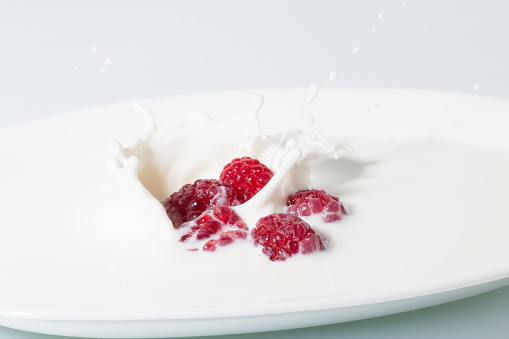 photo shot of raspberries falls into milk