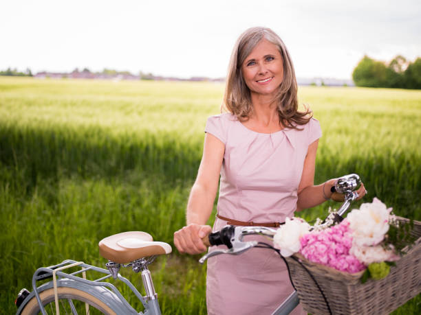 istock Smiling mature woman standing with her bicycle in a park 480331686