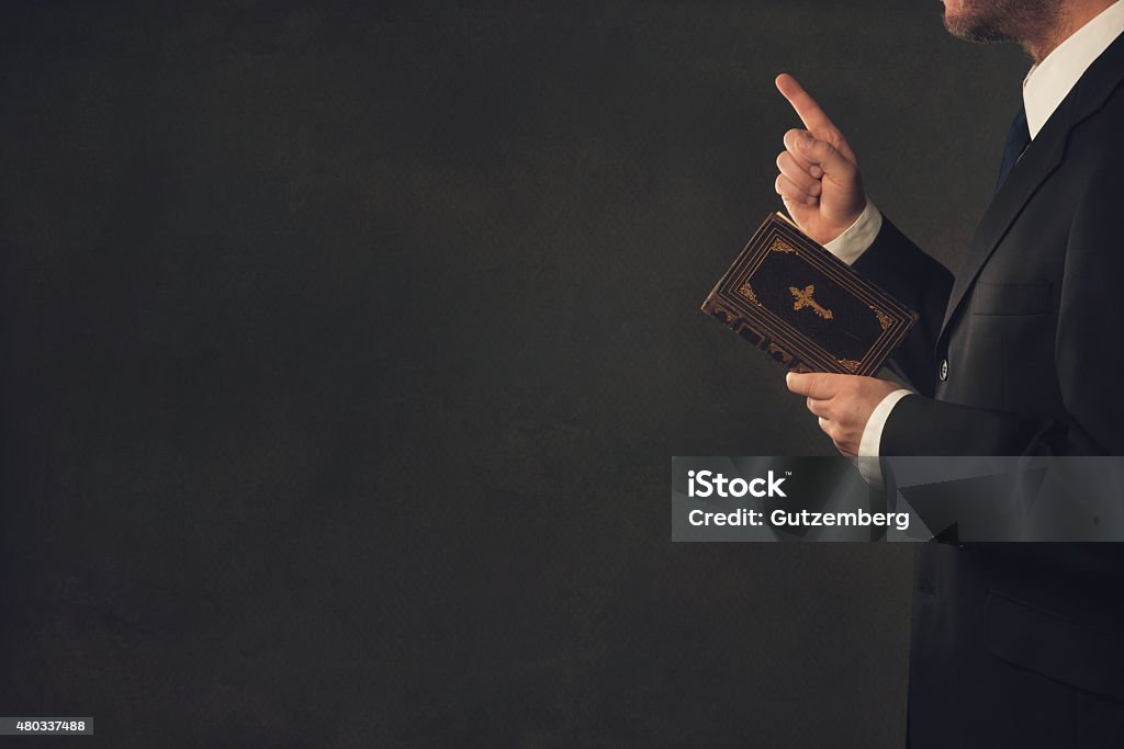 Man with a Bible and a wagging finger A standing man in Suit with a Bible and a wagging finger Preacher Stock Photo