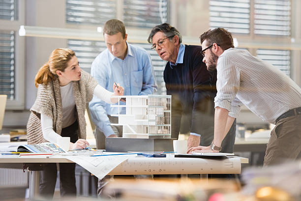 Architect explaining project plan to client Architect explaining project plan to client in office with the help of an architectural model. Project manager and co-worker standing beside him. architectural model photos stock pictures, royalty-free photos & images