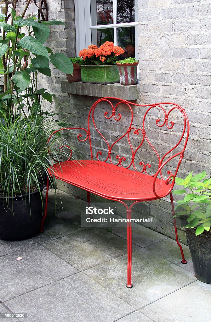 Red bench outside on a patio Red wrought iron bench outside on a garden patio. Patio Stock Photo