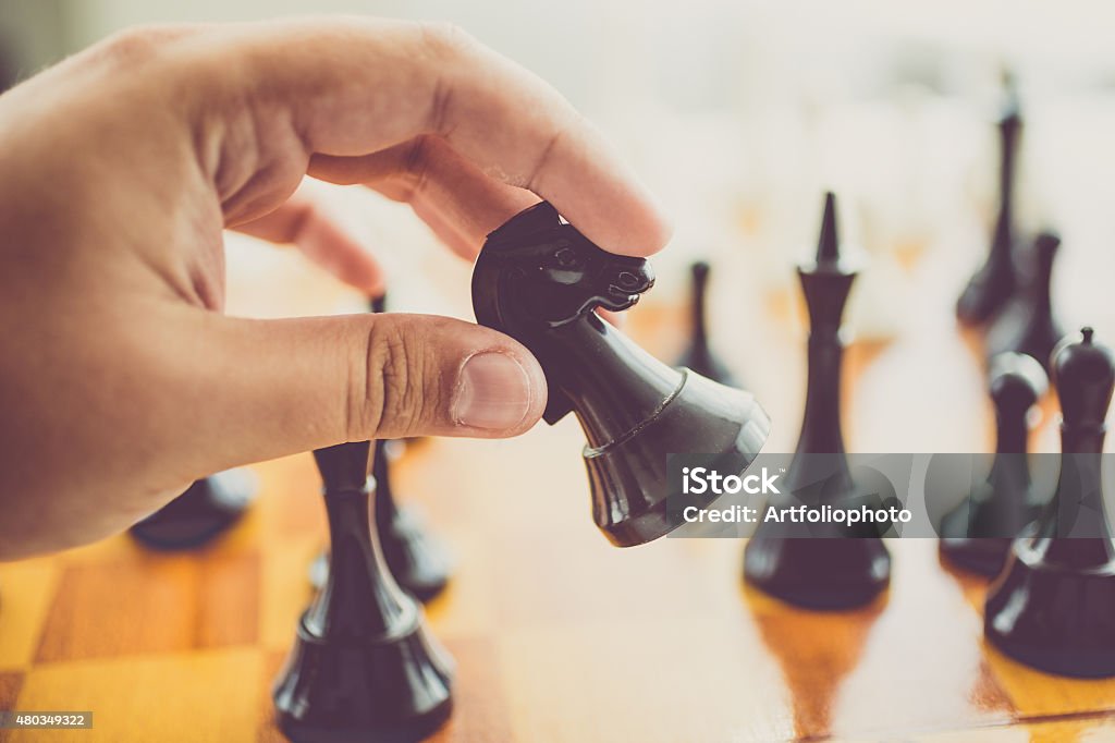 closeup of man making move with black piece at chess Closeup toned photo of man making move with black horse at chess game Chess Stock Photo