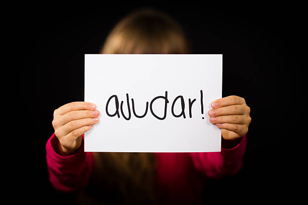 istock Child holding sign with Portuguese word Ajudar - Help 480357956