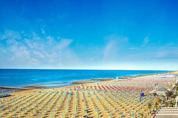 mare e spiaggia con ombrelloni sulla ble sfondo cielo - romagna foto e immagini stock