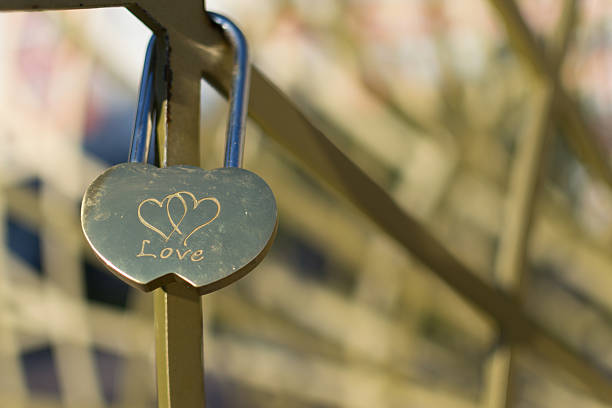 Single golden love padlock with two linked hearts