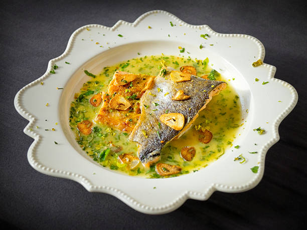 Pan-fried sea trout in green sauce with fried garlic slices.