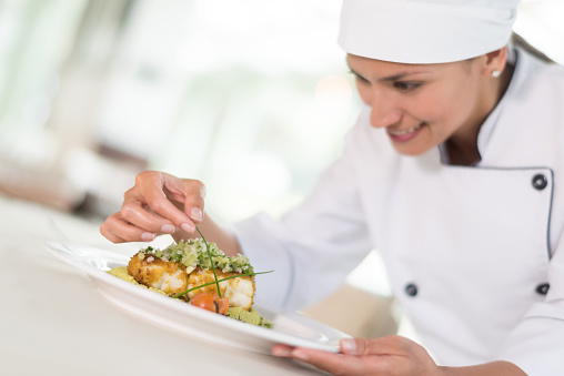 Chef decorating a beautiful plate at a restaurant and looking happy cooking